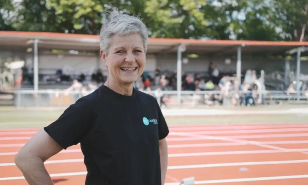 Lene Fisk, arrangør af STU atletikstævnet, står på atletikbanen på Langvang Stadion og følger dagens aktiviteter med et smil.