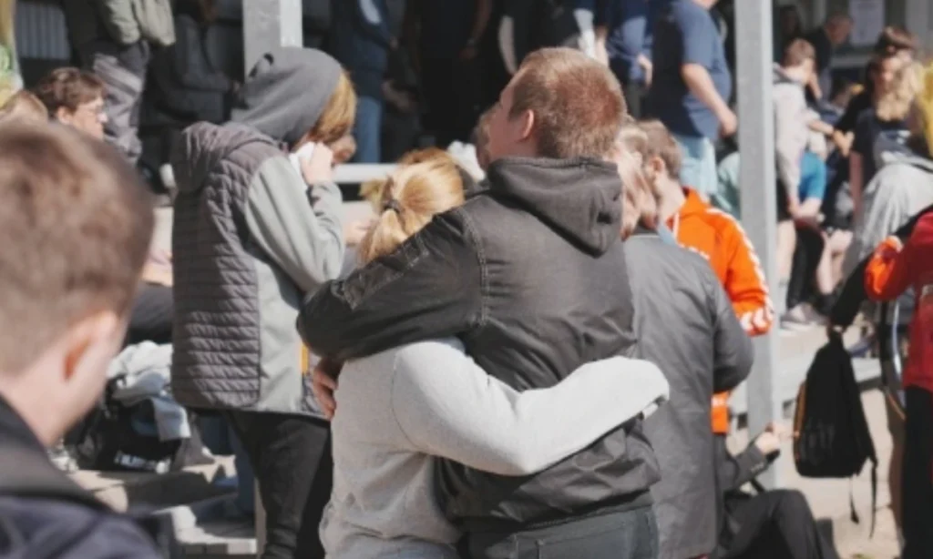 Deltagere og personale krammer og fejrer sammen på tribunerne under STU atletikstævnet, som viser det varme fællesskab og den støttende atmosfære ved arrangementet.