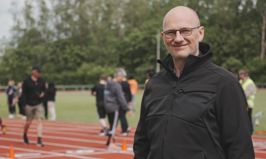 Skoleleder Poul Block fra STU Randers står på atletikbanen og smiler til kameraet under STU atletikstævnet på Langvang Stadion.